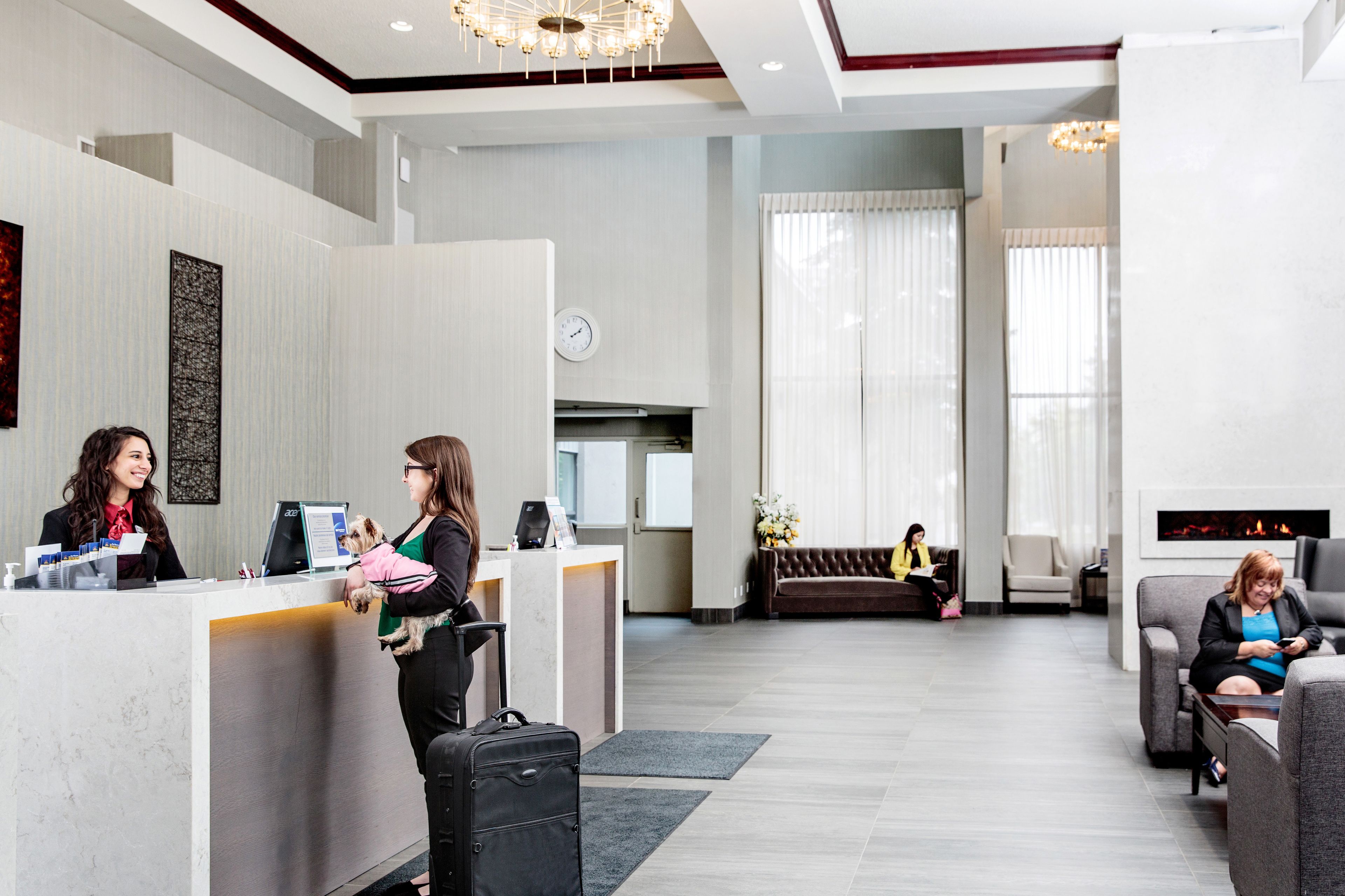 Un hall d’hôtel moderne comprenant un comptoir d’accueil, un espace salon et une cheminée.