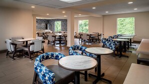 A dining area with round tables and chairs, some with blue patterned upholstery.