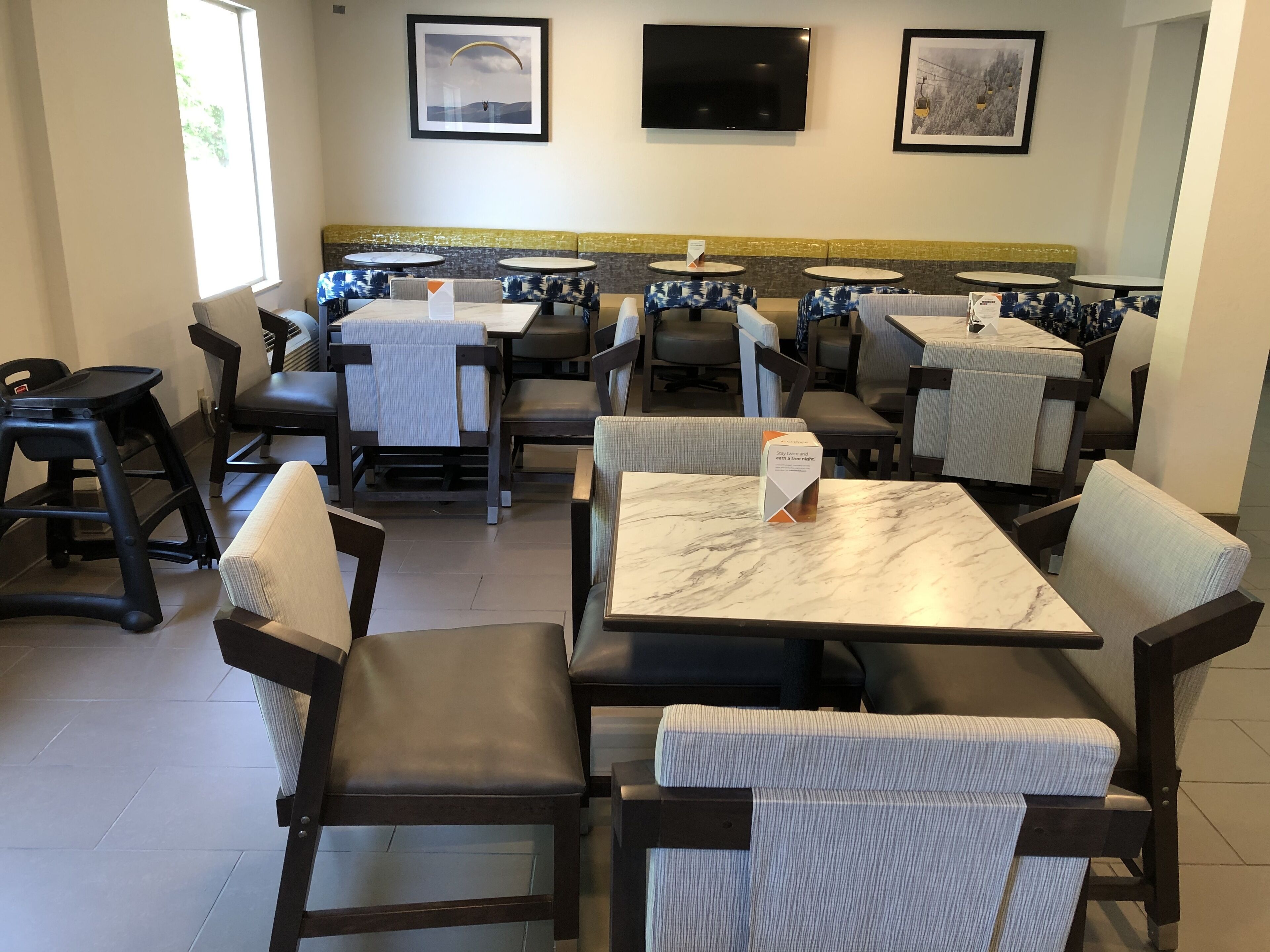Un restaurant amb seients en cabines i taules, algunes amb cartes. Hi ha quadres al mur i una televisió sobre les cabines.
