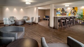 A modern lobby with seating areas, a bar, and a mural on the wall.