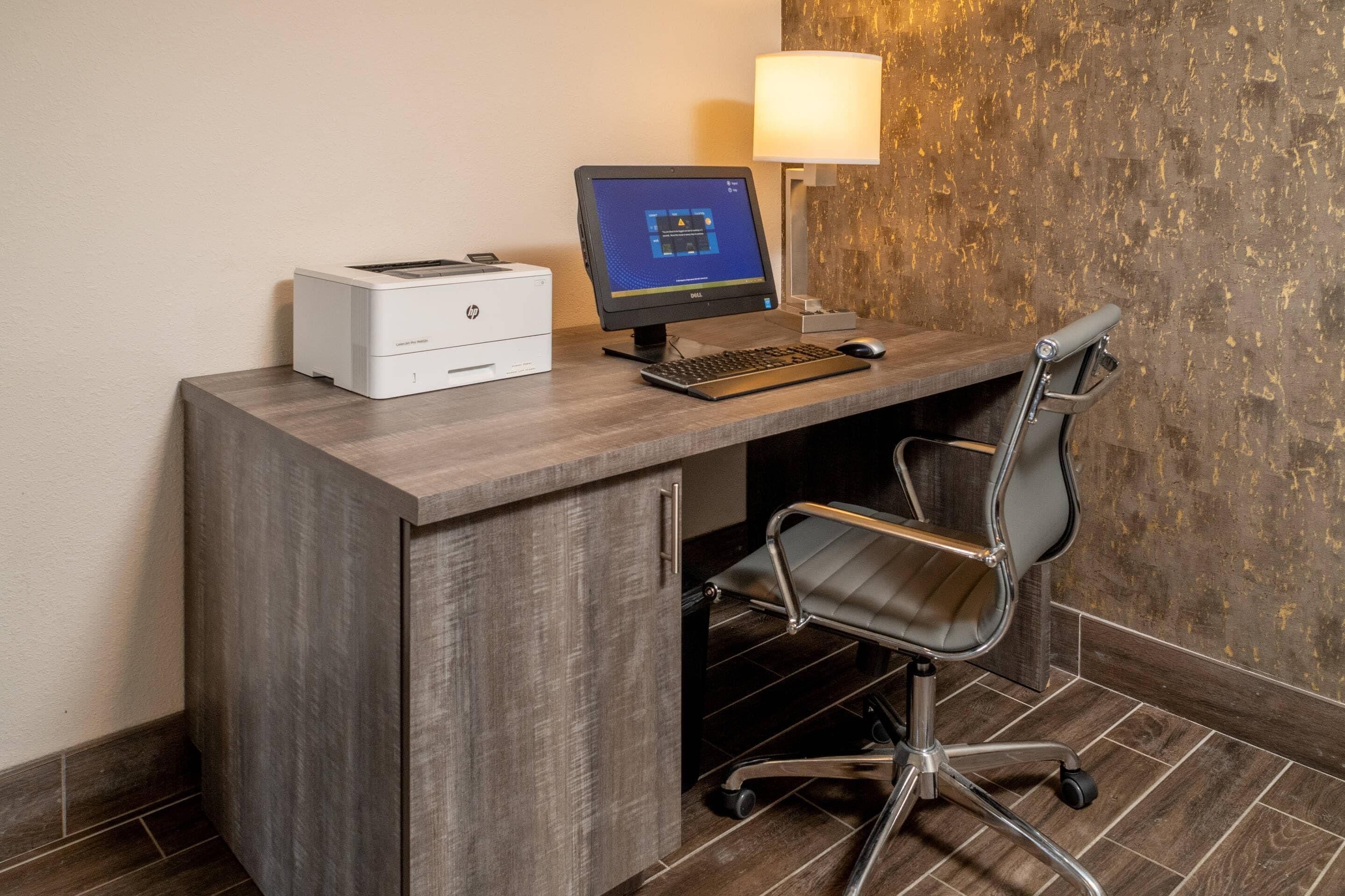 A modern office desk with a desktop computer, a printer, and a chair.