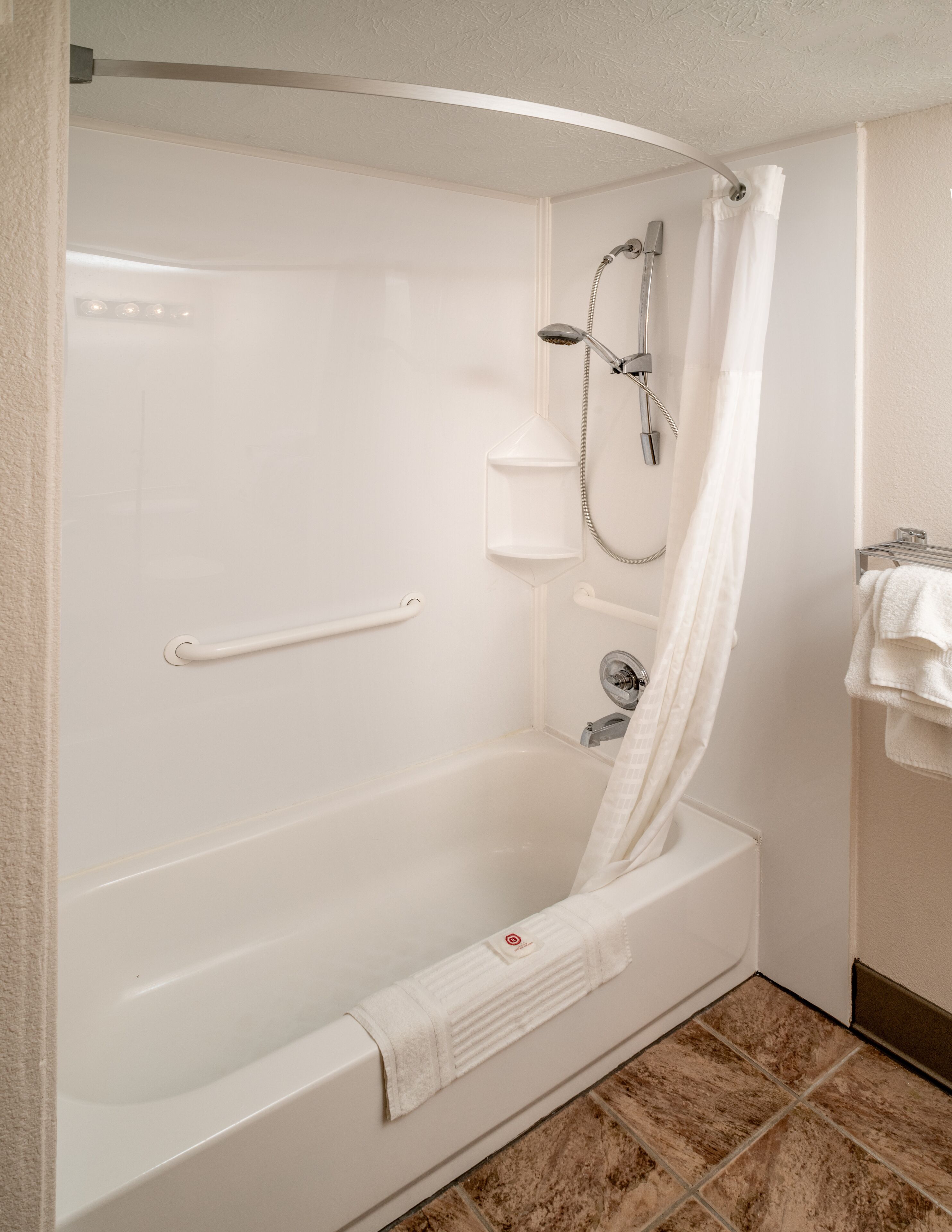 A modern bathroom with a white bathtub, a shower with a handheld showerhead, and a towel rack.