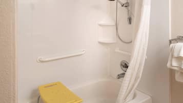 Une salle de bain avec une baignoire, une douche, un porte-serviettes blanc, un rideau de douche blanc et un petit tabouret jaune.