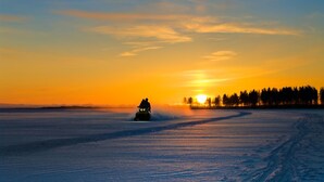 A snowmobile on a frozen lake at sunset.