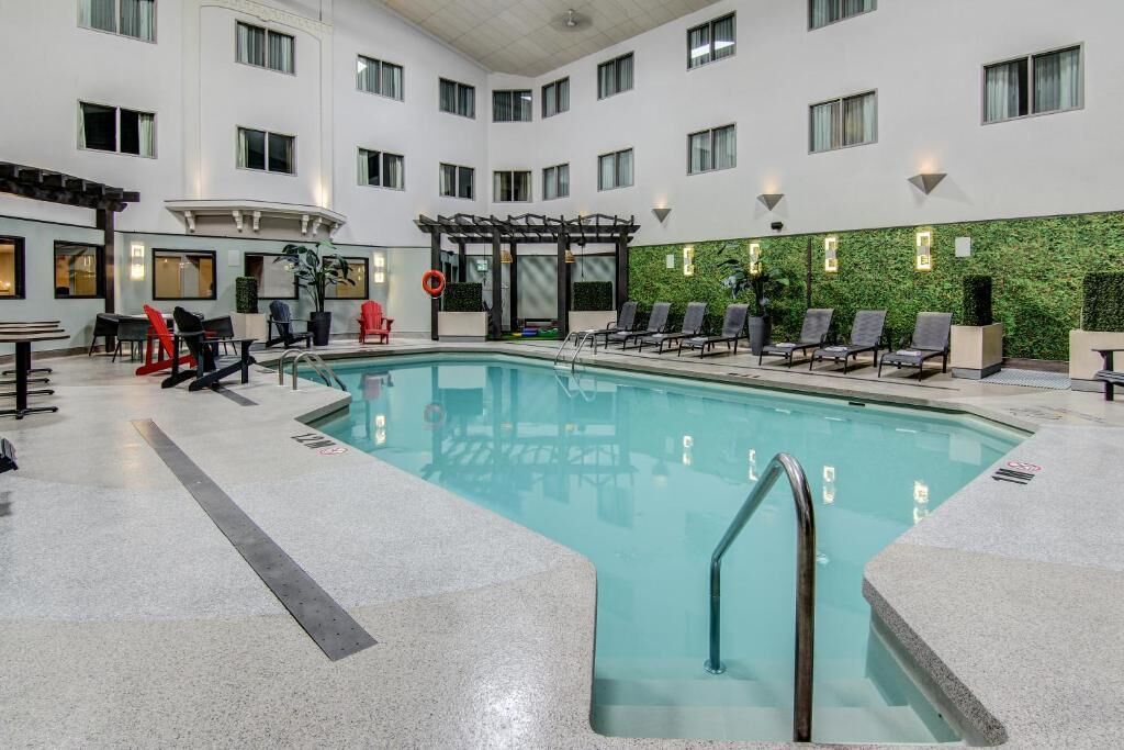 An indoor swimming pool with lounge chairs and a pergola.