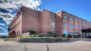 A multi-story hotel with a brick facade, a covered entrance, and a parking lot.