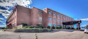 A multi-story hotel with a brick facade, a covered entrance, and a parking lot.
