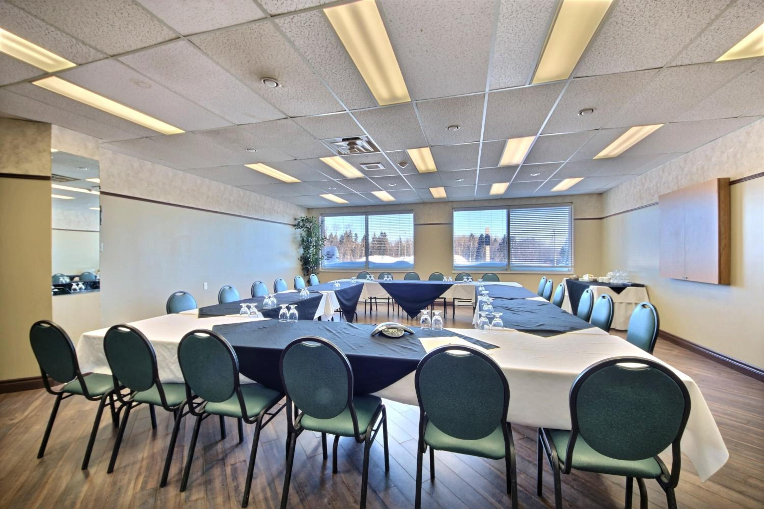 Une salle de conférence dotée d’une grande table ovale, de plusieurs petites tables et de chaises.