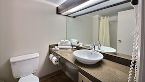 A bathroom with a white toilet, a sink with a mirror above it, and a hairdryer on the wall.