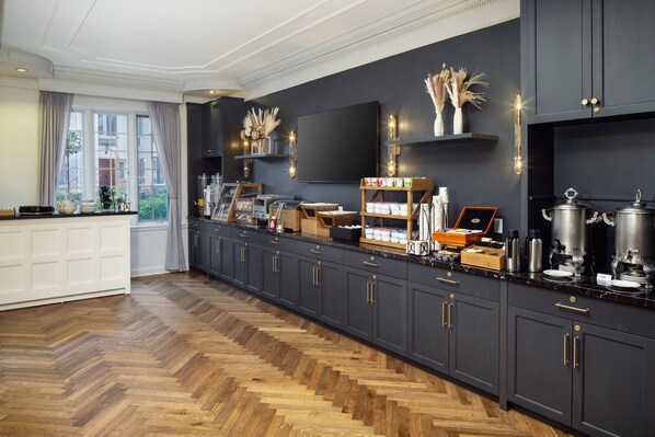 A modern kitchen with dark cabinetry, a herringbone wood floor, and a large window with curtains.
