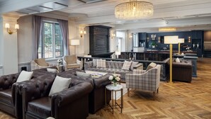 A spacious living area with a fireplace, plush seating, and a herringbone wood floor. - Madison Hotel (Morristown)