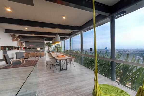 A modern interior with a dining area, kitchen, and large windows offering a city view.