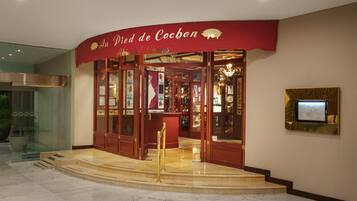 A hotel entrance with a red awning, glass doors, and a display case with items inside.