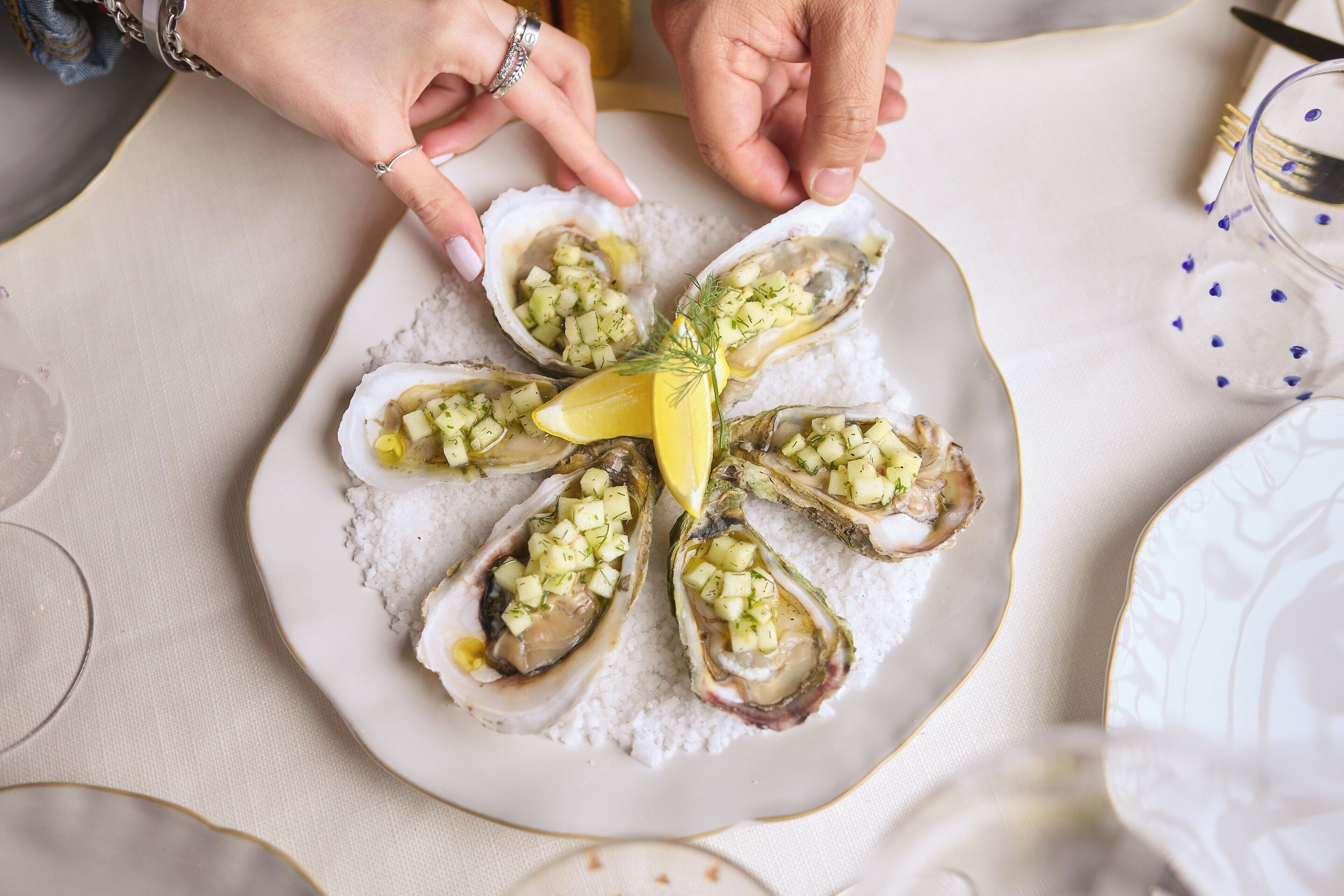 A plate of oysters with a lemon garnish.