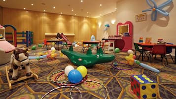 Zona de juegos infantiles con un tobogán, juguetes inflables y un barco de juguete.