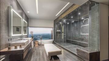 A modern bathroom with two sinks, a large bathtub, and a glass-enclosed shower area.