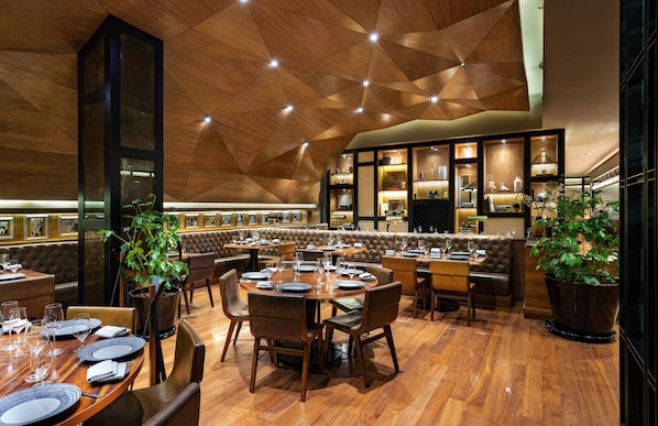 Un restaurante con suelo de madera, mesas redondas y asientos de cuero.