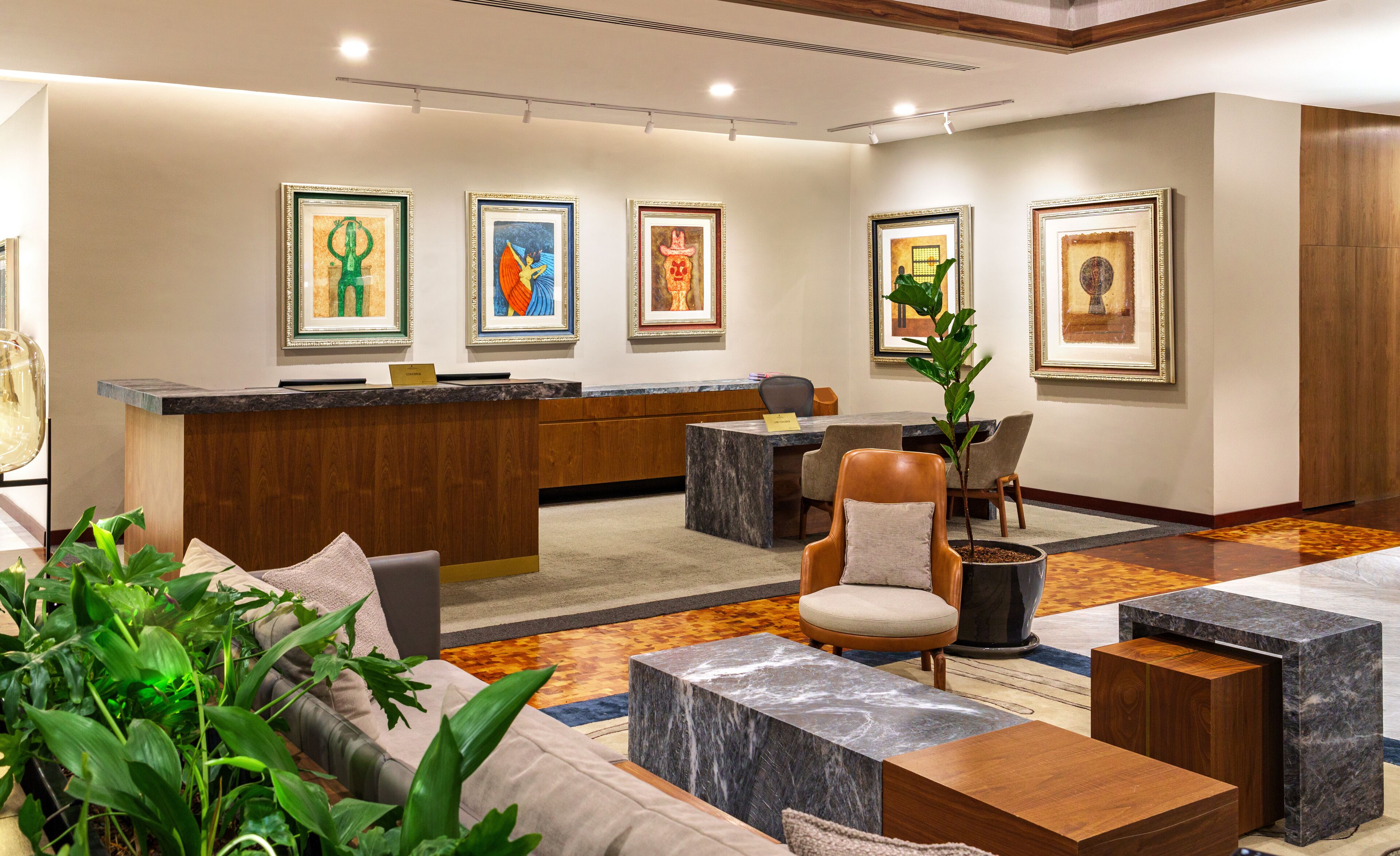 A lobby with a reception desk, seating area, and artwork on the walls.