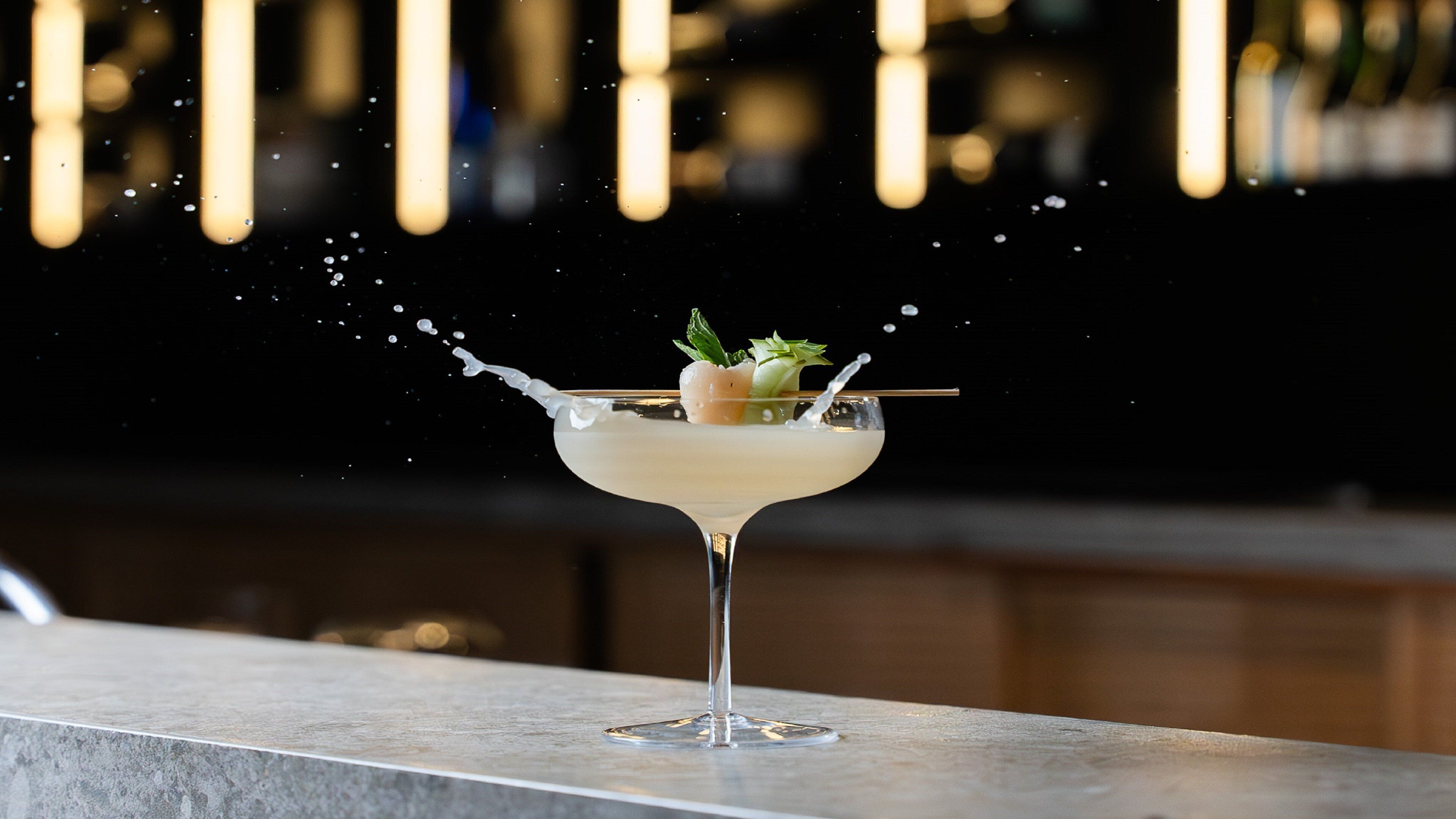 Et cocktailglas med en skvæt væske på en bardisk.