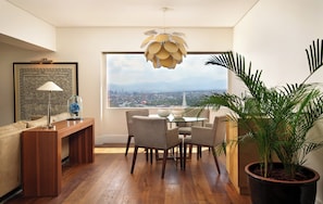 Un comedor moderno con una mesa y sillas de madera, una lámpara colgante y un ventanal con vistas a la ciudad.