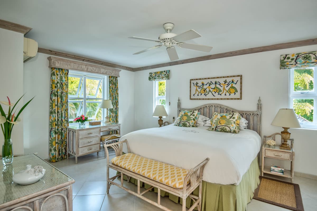 A bedroom with a bed, bedside table, lamp, window, and a ceiling fan.