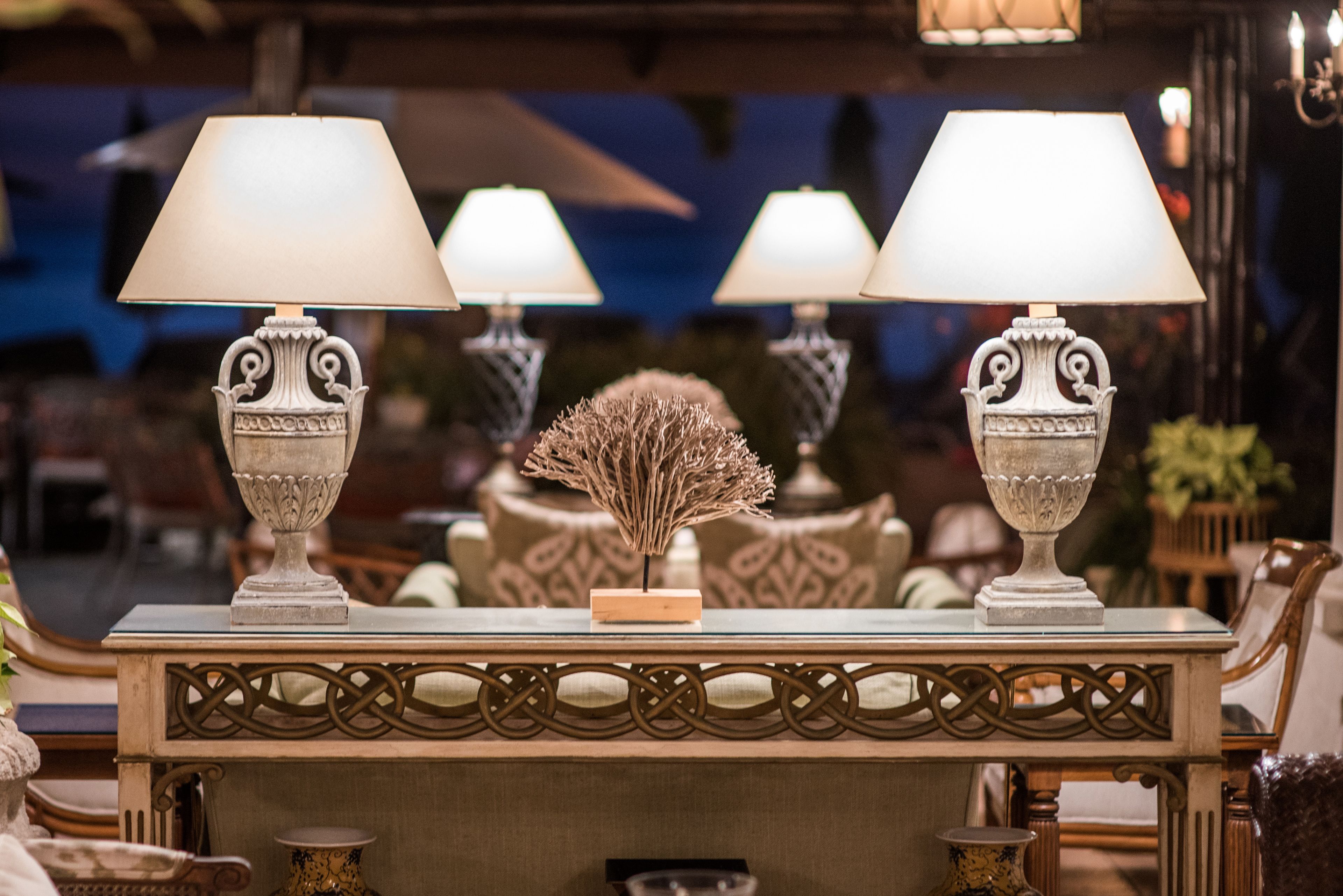 A table with three ornate lamps and a decorative centerpiece.