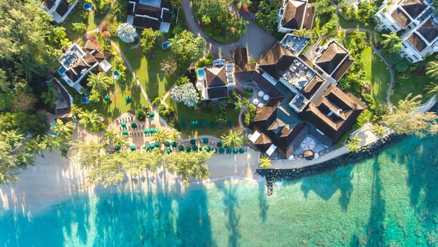 An aerial view of a resort with multiple buildings, a beach, and clear turquoise waters. - Coral Reef Club (Holetown)