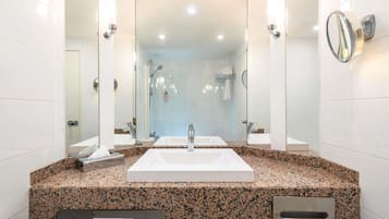 A modern bathroom with a large sink, two mirrors, and a shower area.