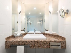 A modern bathroom with a large sink, two mirrors, and a shower area. - Mercure Paris CDG Airport & Convention (Roissy-en-France)