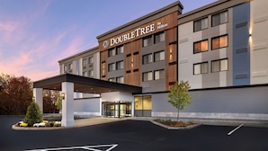 A DoubleTree by Hilton hotel with a modern facade, a covered entrance, and a landscaped area with a small tree. - DoubleTree by Hilton Downtown Concord (Concord)
