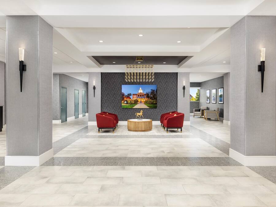 A spacious lobby with a modern chandelier, a large wall mural, and seating areas.
