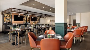 A restaurant with a bar area, multiple tables, and chairs. - DoubleTree by Hilton Downtown Concord (Concord)