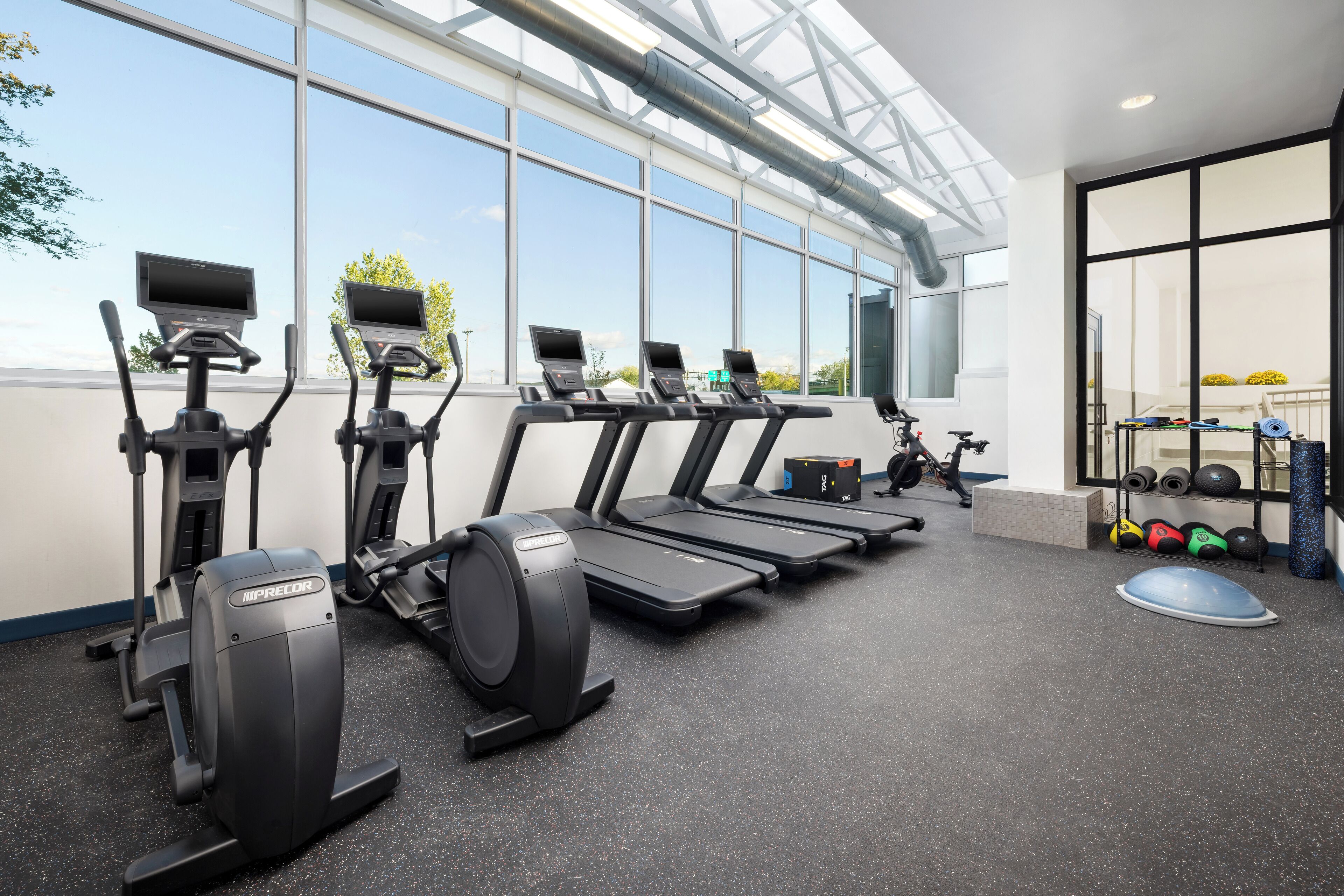 A gym with treadmills, elliptical machines, and a weight rack.