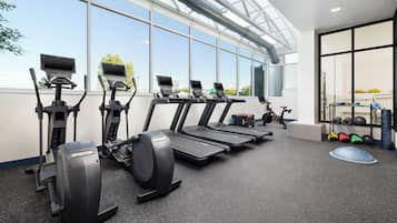 Un gimnasio con cintas de correr, elípticas y una estructura para pesas.