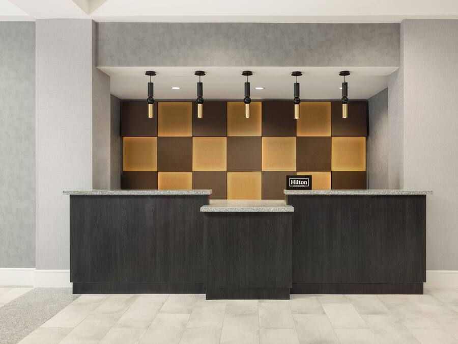 A reception desk with a check-in counter, a wall with a geometric pattern, and a logo on the wall.