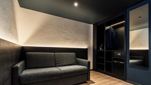 Ein modernes Zimmer mit grauem Sofa, Holzboden, eingebautem Wandschrank und einer deckenebnen Leuchte.