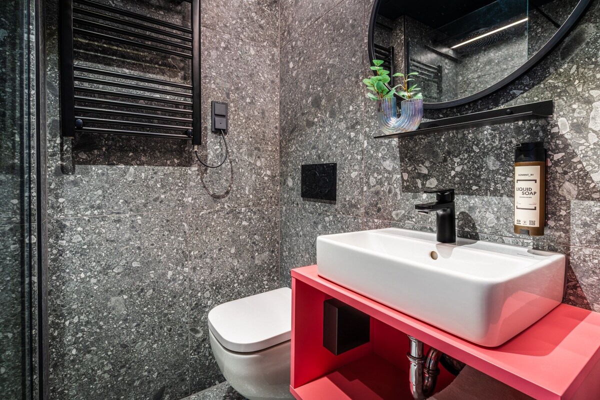 Ein modernes Badezimmer mit einem weißen Waschbecken, einer roten Kommode und einer Toilette.