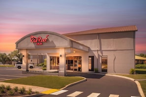 Un hôtel Red Roof Inn au design moderne, doté d’une grande entrée et d’un parking.