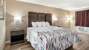 A hotel room with a bed, two bedside tables with lamps, a headboard, and a window with curtains. - Red Roof Inn Manchester, TN (Manchester)