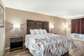 A hotel room with a bed, two bedside tables with lamps, a headboard, and a window with curtains. - Red Roof Inn Manchester, TN (Manchester)