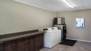 A laundry area with a washing machine, dryer, and a small refrigerator. - Red Roof Inn Manchester, TN (Manchester)