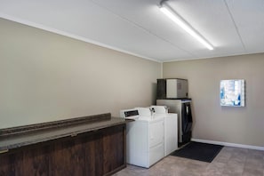 A laundry area with a washing machine, dryer, and a small refrigerator. - Red Roof Inn Manchester, TN (Manchester)