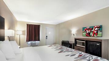 Une chambre d’hôtel avec un lit, un bureau, une télévision et une porte.