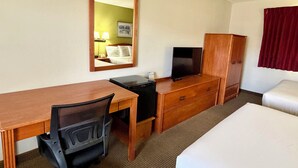 A hotel room with a bed, desk, chair, television, wardrobe, and a mirror. - Americas Best Value Inn St. Ignace (St Ignace)