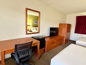 A hotel room with a bed, desk, chair, television, wardrobe, and a mirror. - Americas Best Value Inn St. Ignace (St Ignace)