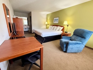 Quarto de hotel com cama, escrivaninha, cadeira e uma pequena mesa.