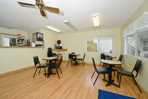 Relax in this spacious room with a high ceiling, featuring a coffee machine, refrigerator, and comfortable seating areas.