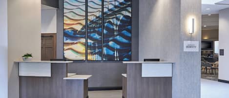 Ett receptionsområde med två diskar, en stor abstrakt målning och en skylt för Marriott Bonvoy.