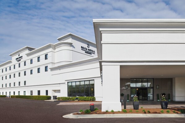 A modern hotel building with a sign reading "Delta Hotels."