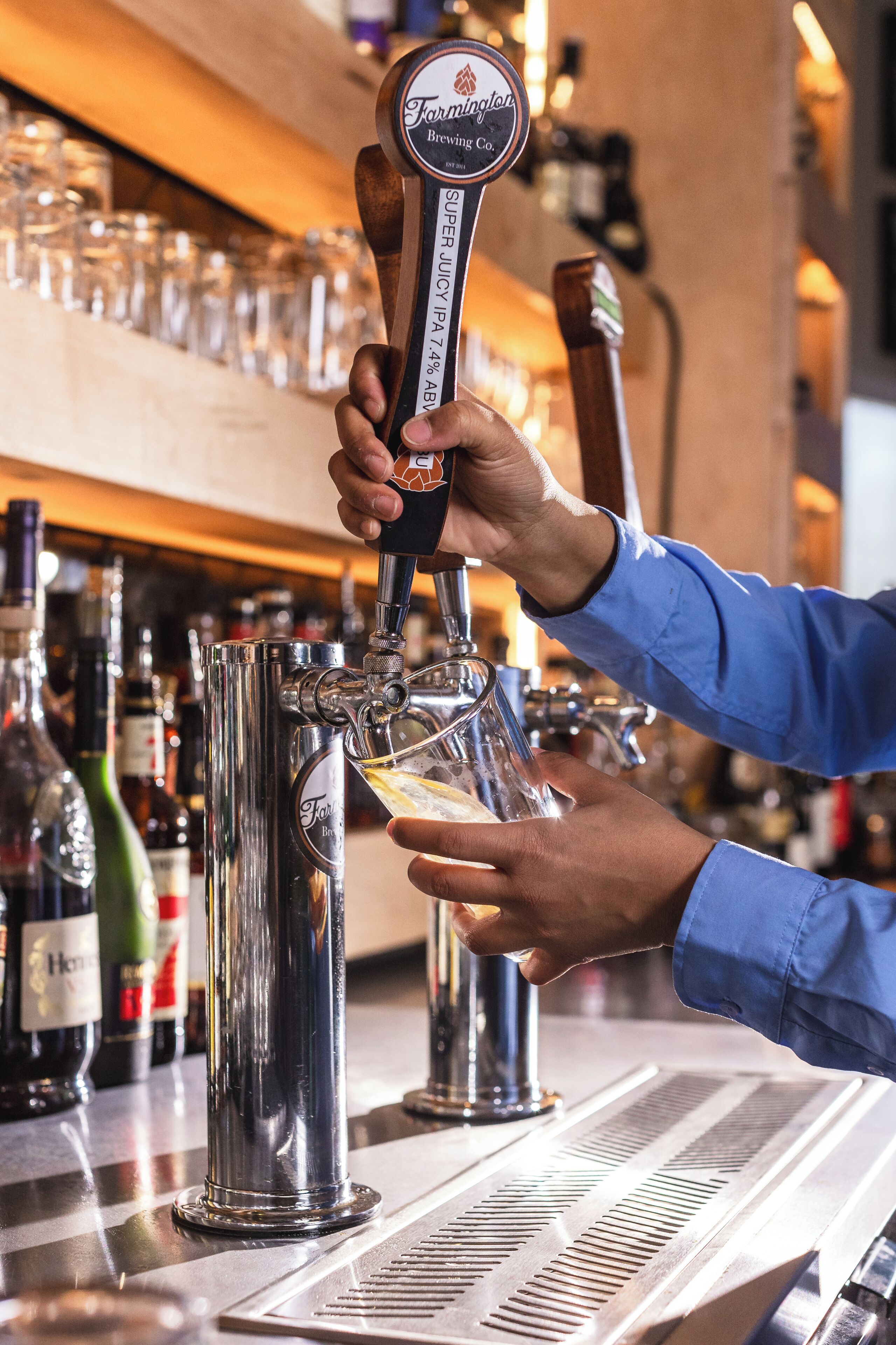 A bartender pouring beer into a glass at a bar.